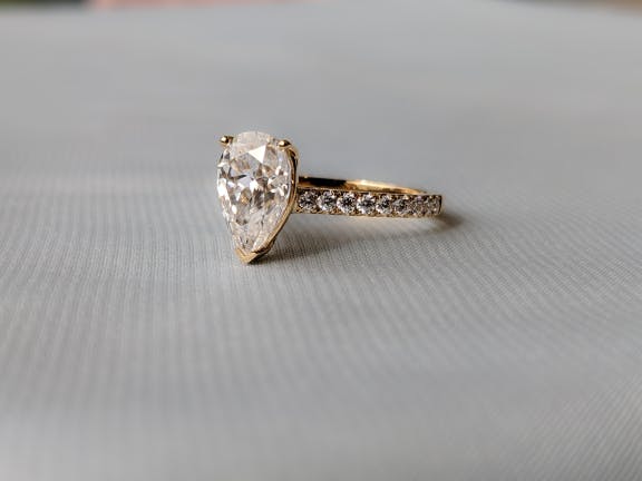 Solitaire Pear Cut in Gold with Melee Diamonds