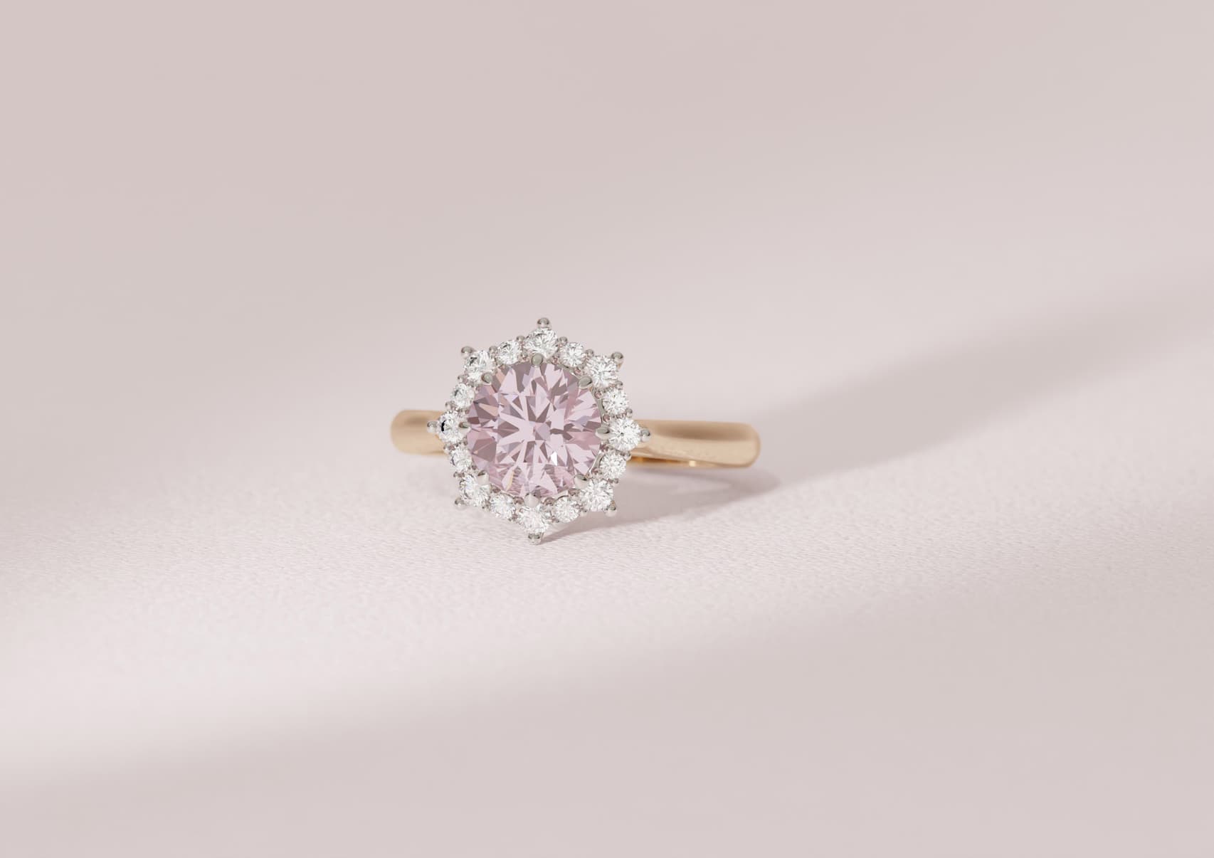 1.5 carat pink diamond solitaire with a white diamond halo in a yellow gold band