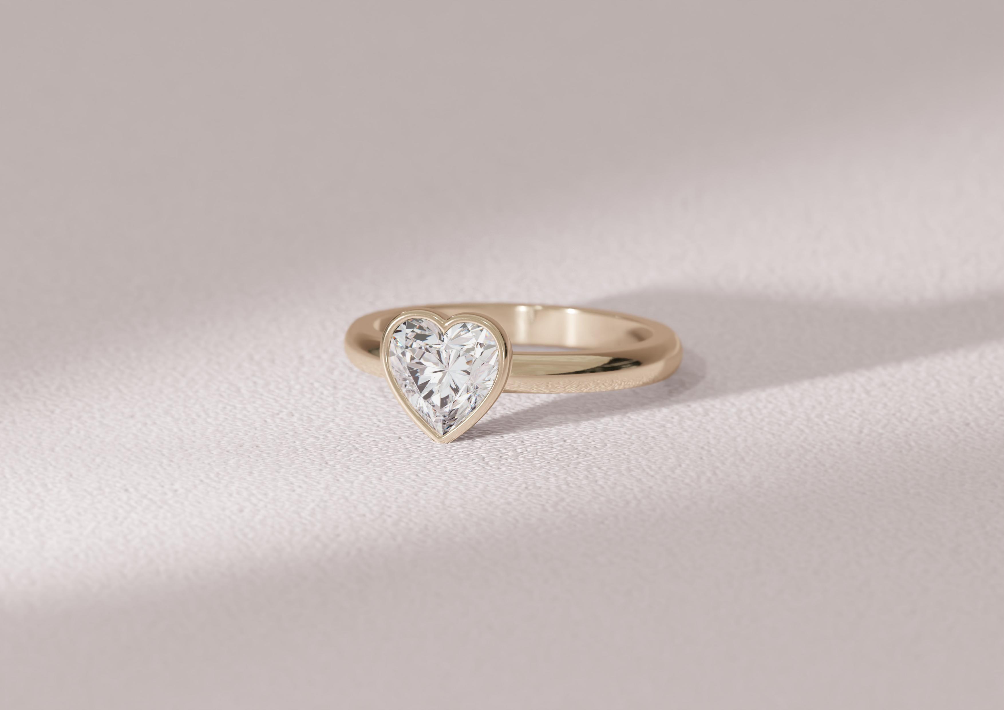 Heart cut lab grown diamond engagement ring in full bezel in a yellow gold band.