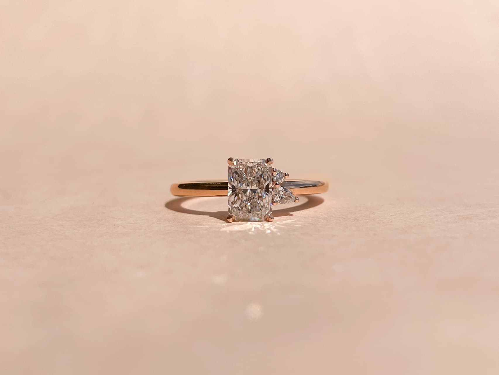 Radiant cut diamond with two accenting pear diamonds in a yellow gold band 