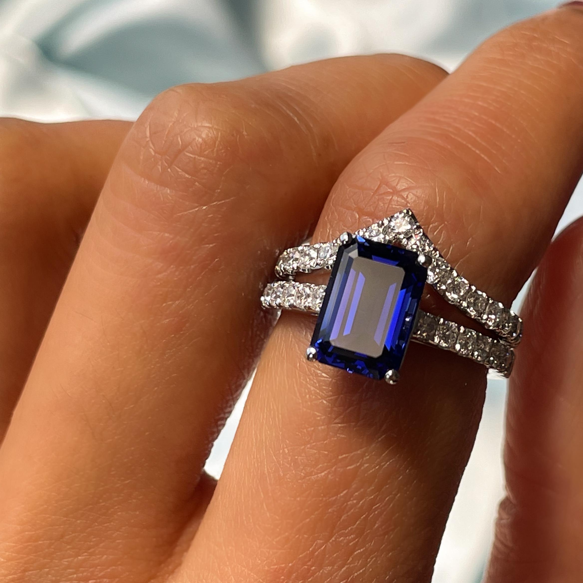 Bridal set featuring an emerald cut sapphire engagement ring in a platinum band and curved wedding ring both with pave diamonds 