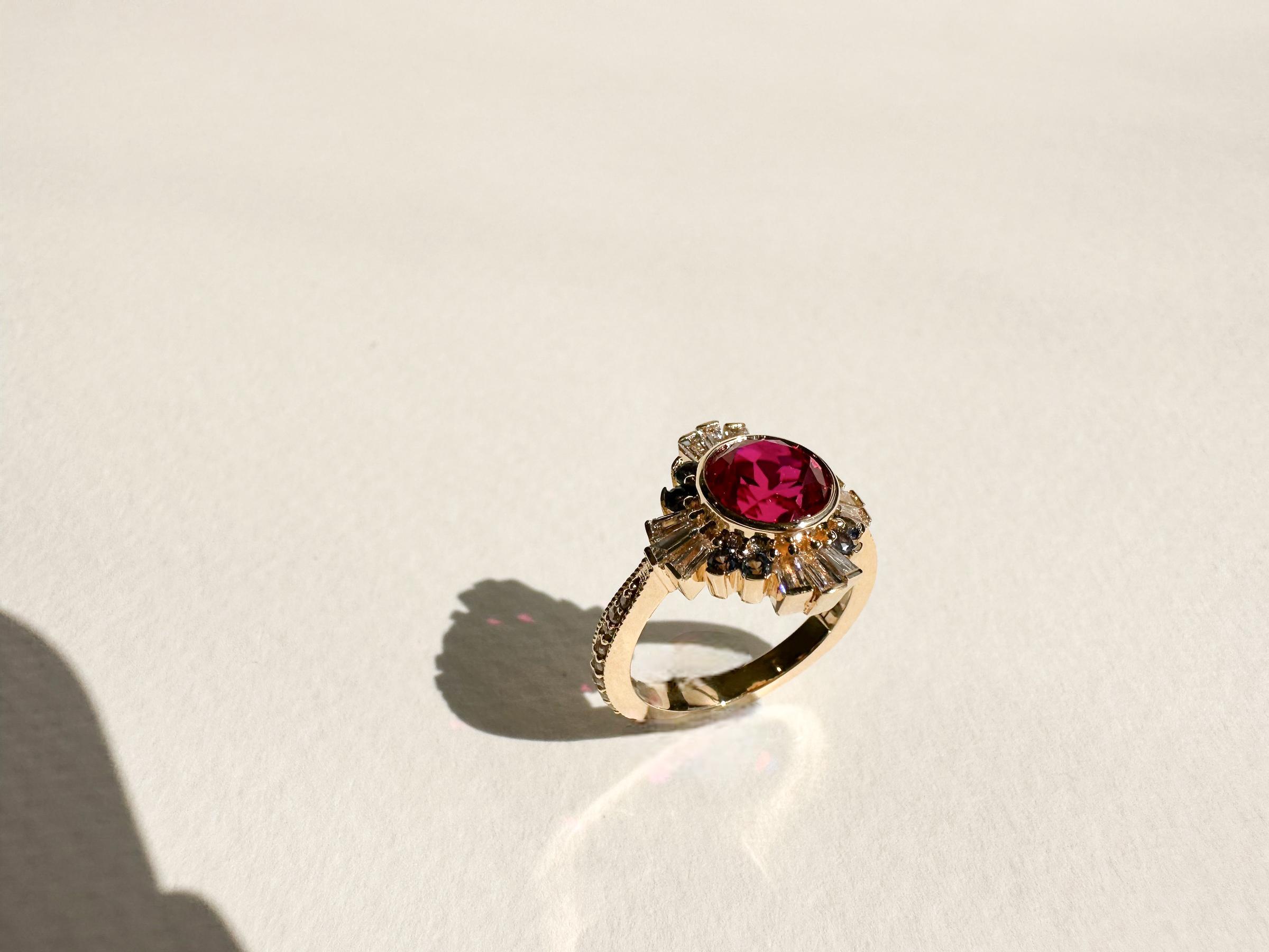 1.5 carat ruby solitaire engagement ring featuring asymmetric halo and channel set diamonds along the band with milgrain in yellow gold.