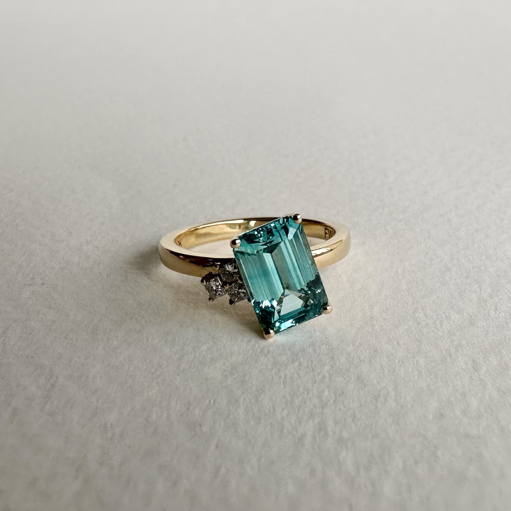 Asymmetrical teal sapphire engagement ring with accenting stones in 14K yellow gold