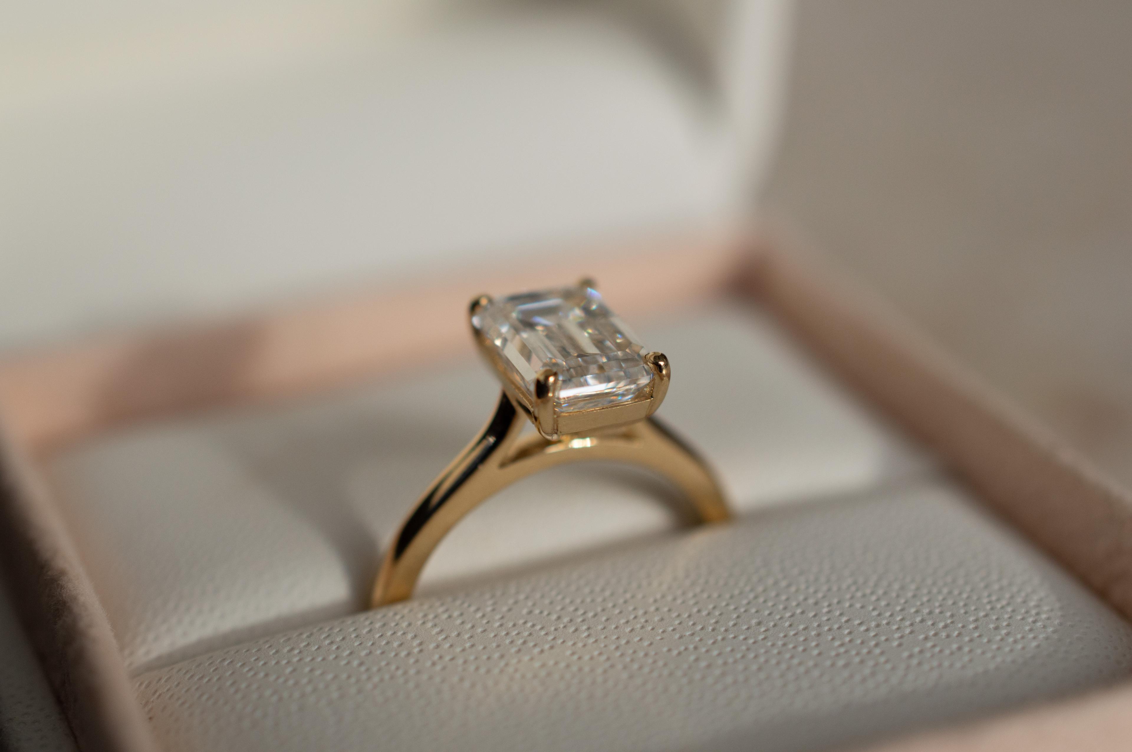 Emerald cut diamond with single bead prongs in a yellow gold band