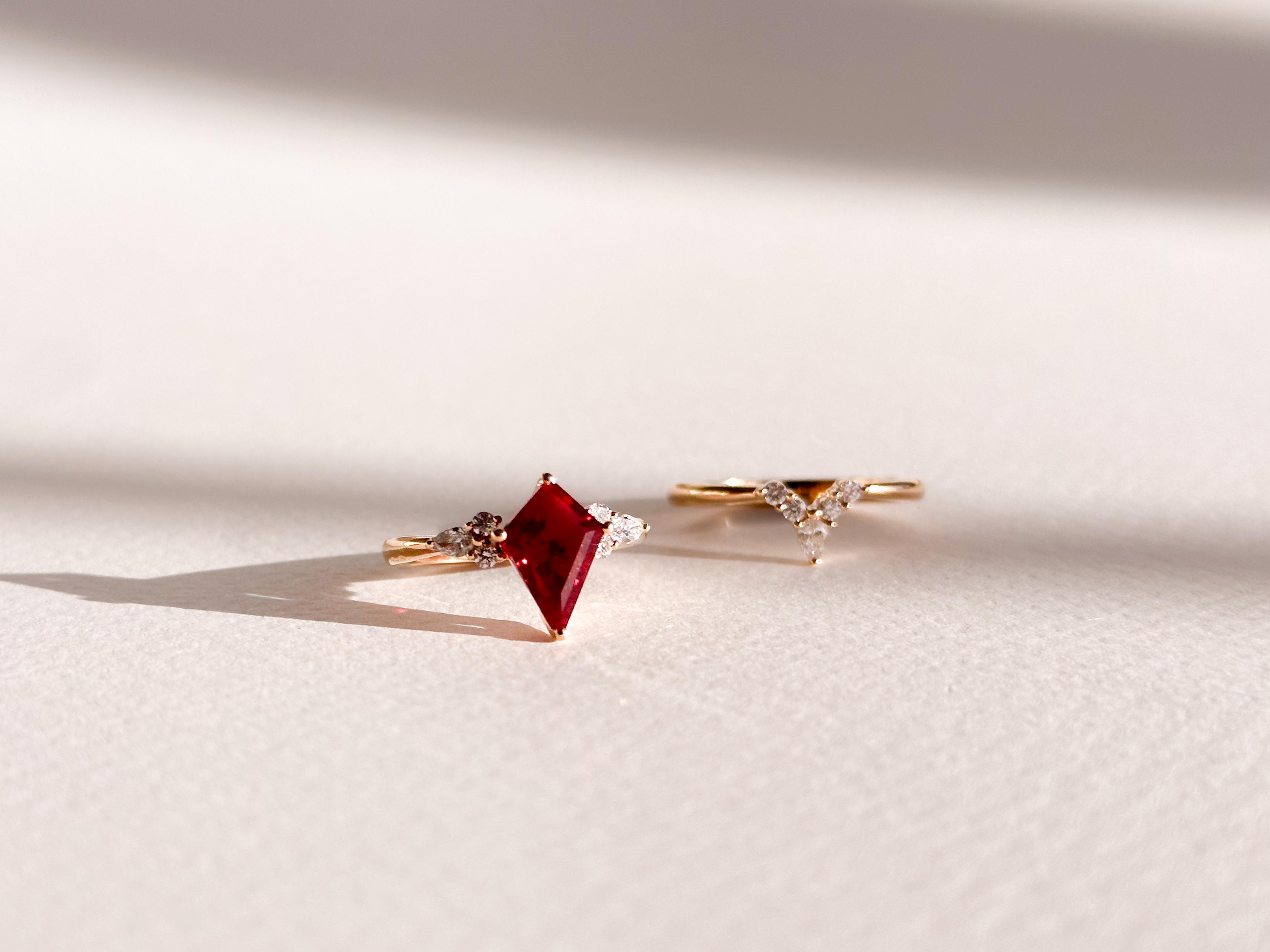 Kite cut ruby engagement ring with six accenting round diamonds in a yellow gold band with a flush fit wedding ring.