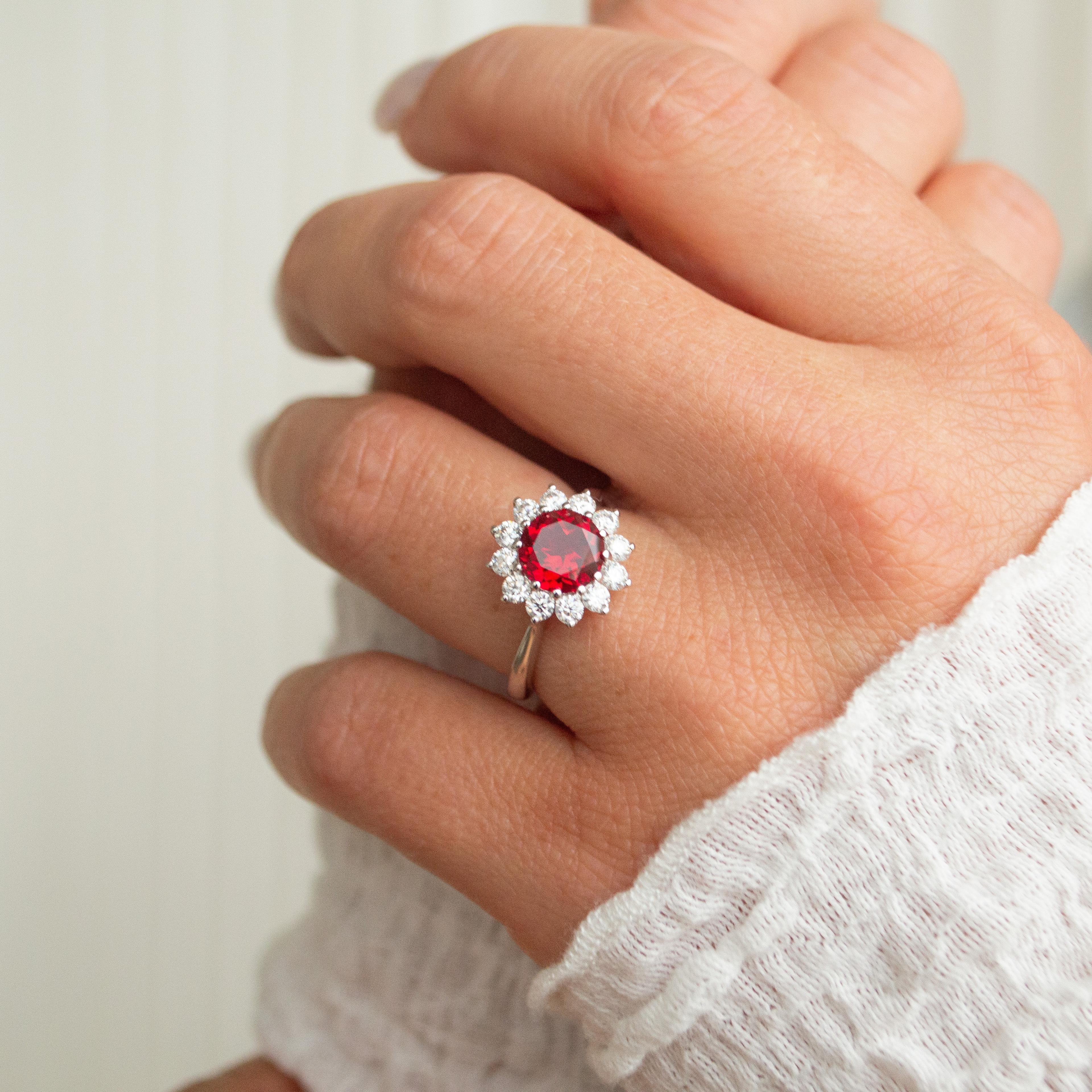 1 carat round cut ruby with diamond halo in a yellow gold band.